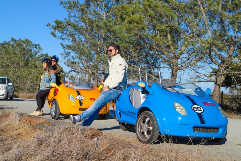 Blue and Yellow GoCars Parallel Parked with Smiling tourists near by