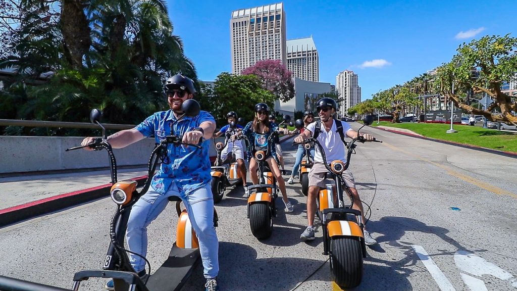Six Fat Tire Scooters and Passengers Driving on the Road in San Diego