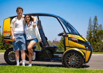 Couple standing on grass next to gocar