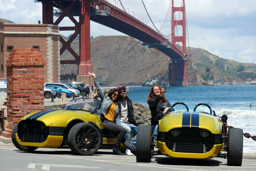 group posing for a photo in front of yellow vanderhall blackjack gocars and golden gate bridge