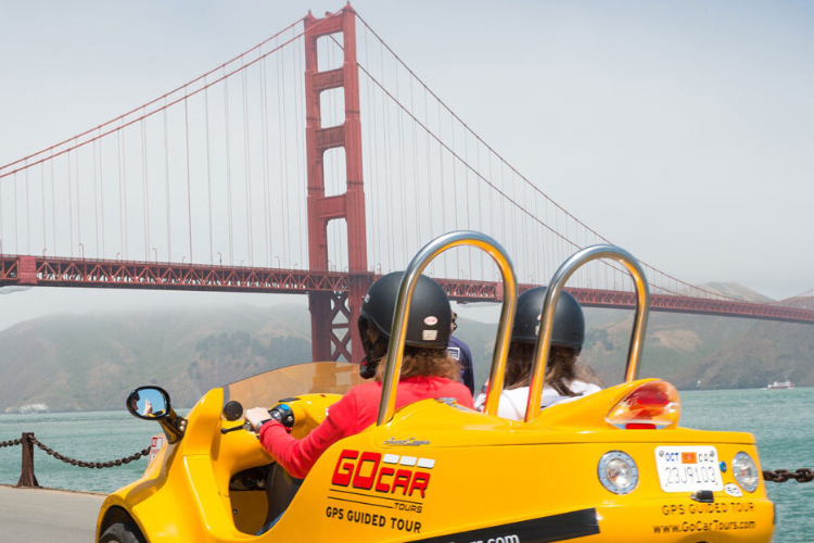 a GoCar driving with the Golden Gate Bridge in the background