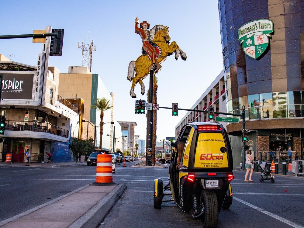 GoCar tour in downtown Las Vegas with a neon sign of a cowboy on a horse on fremont street near Hennessey's Tavern