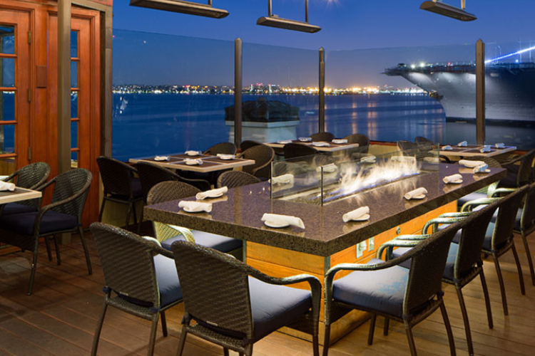rooftop dining on the north deck at San Diego's Top of the Market with views of the harbor and navy ship in the background